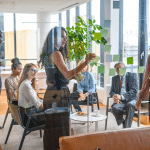 Team of senior care recruiting executives meet in a semi circle in an office setting with windows