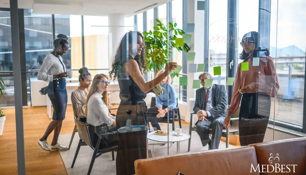 Team of senior care executives meet in a semi circle in an office setting to discuss succession planning