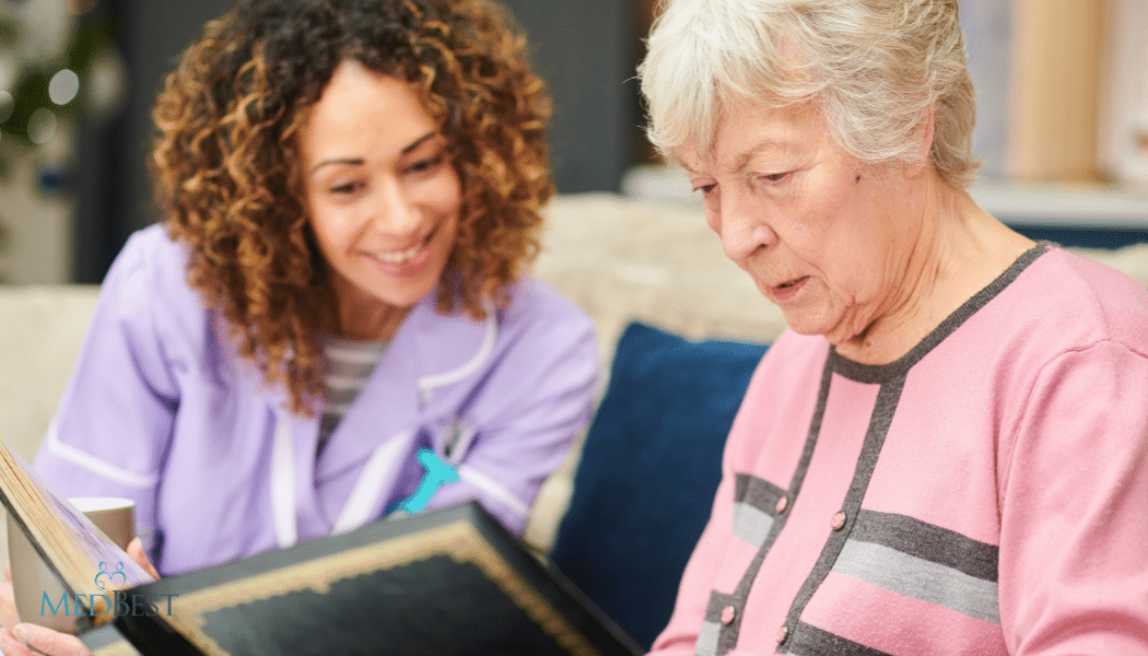 Female Memory Care Director looking at photo album with female resident in a courtyard