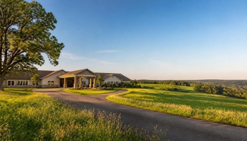 Rural skilled nursing facility surrounded by open farmland at sunset